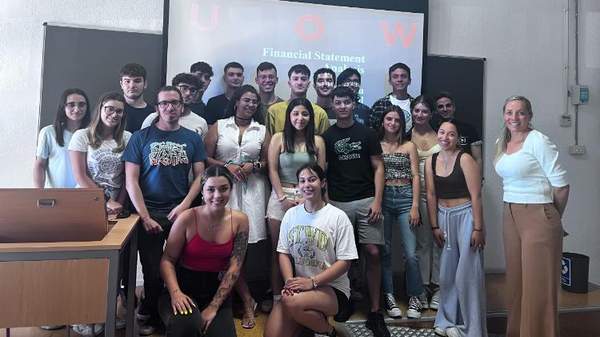 Tina Prodromou, a Lecturer with students in lecture room with a projector screen behind them.