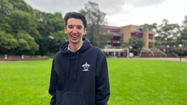 UOW’s Faculty of Business and Law student, Louis Angeli standing on grass wearing a black jumper.