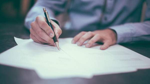 Man wearing business shirt writing with a pen