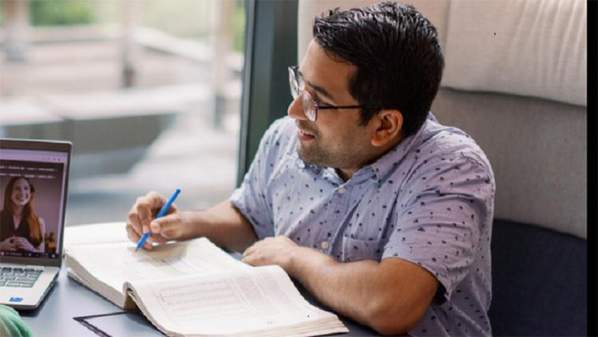 Utkrista Acharya writing in a notebook while sitting by a window.