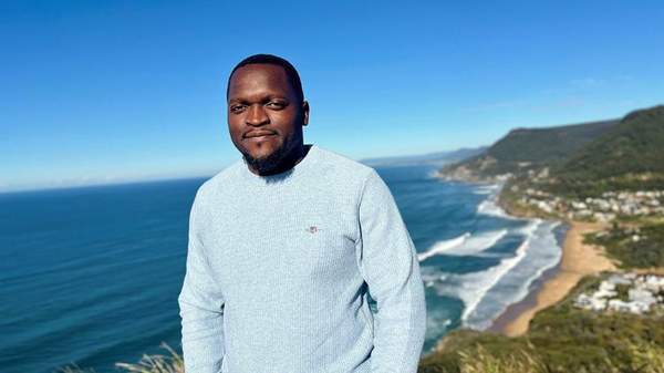 Sydney Business School, UOW’s student Zweli Khoza stands at lookout overlooking Wollongong coastline.