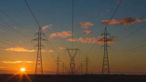 Power grid towers with the sun setting in the background