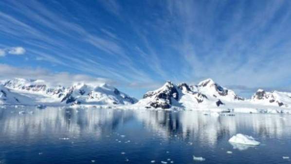 Snow covered mountains of Antarctica, with crystal clear waters in the foreground