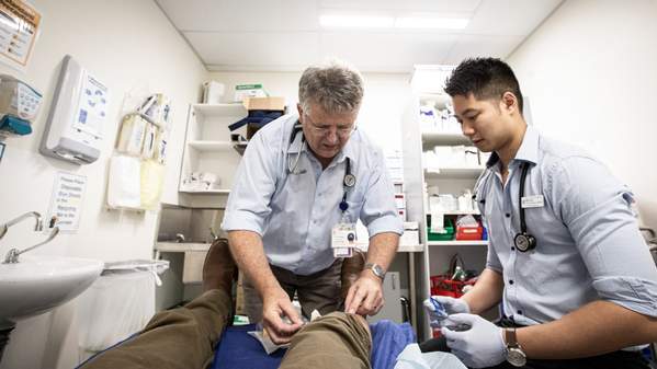 An established GP shows a medical student how to perform a procedure on a patient in a hospital bed. Photo: Paul Jones