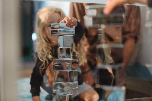A child at the Discovery Space playing with mirrored blocks in The Sanctuary play experience.