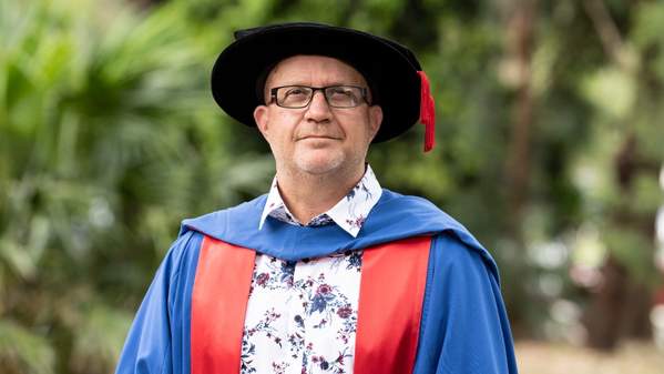 Dr Shawn Burns wears the graduation cap. He is looking at the camera. Photo: Paul Jones