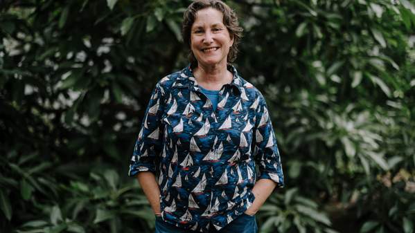 Dr Jen Saunders stands in front of a greenery background with her hands on her hips. Photo: Michael Gray