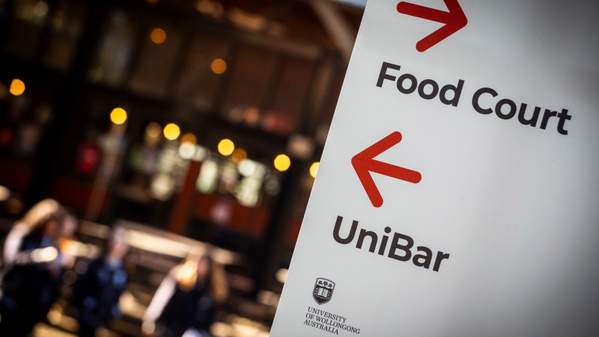 A UOW sign with an arrow to the food court and an arrow to the UniBar