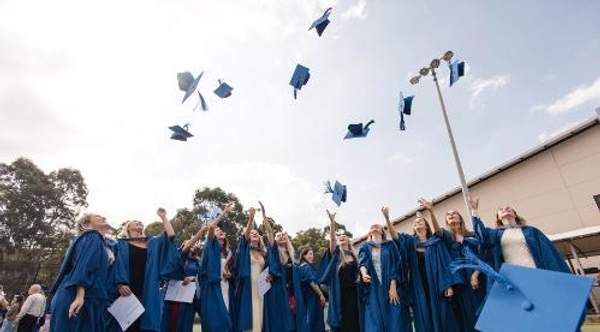 Graduating students from UOW throw their mortarboard caps in the air