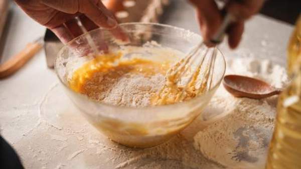 A close-up of a cooking mixing batter in a bowl.