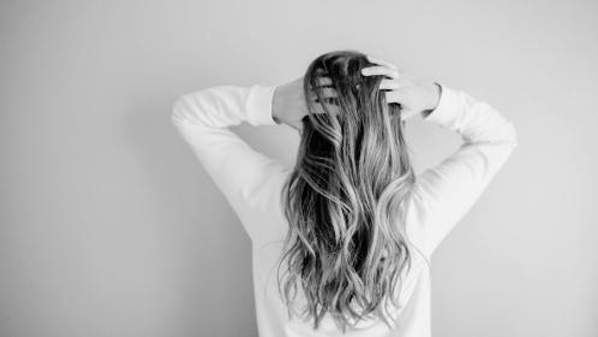 A women running her fingers through her hair from the back