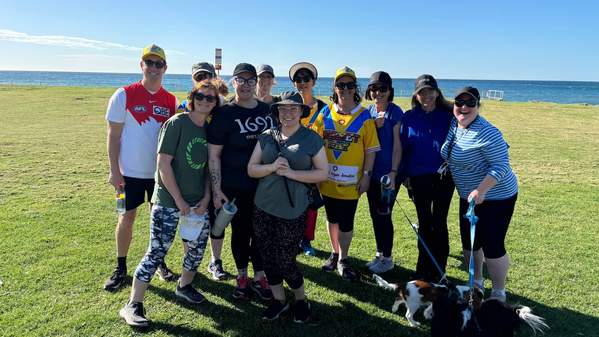 A group of UOW nursing staff stand on the grass in front of the beach, wearing their sporting jerseys, in honour of Dr Kimberley Livingstone. . Photo: Supplied