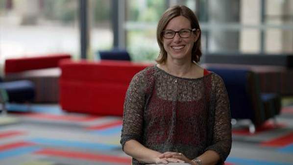 A/Professor Jenny Fisher sitting on a sofa smiling