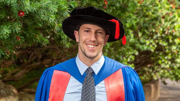 PhD graduate Jordan Sutcliffe portrait in graduation gown by Andy Zakeli
