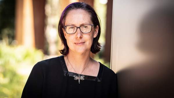 Martina Sanderson-Smith leans against a pole. She wears a black shirt with a dragonfly necklace. Photo: Paul Jones