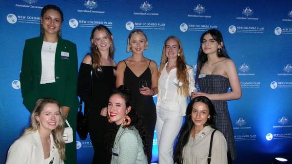 The eight UOW New Colombo Plan Scholars stand in front of a media wall at Parliament House. Photo: Supplied