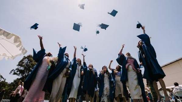 UOW graduates throw their mortarboards in the air after the completion of their graduation ceremony.
