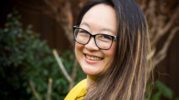 Dr Patti Shih is wearing a yellow shirt and glasses, smiling