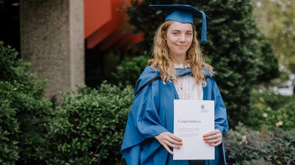 UOW graduate Molly Lasker wears a blue graduation gown and cap in front of Shoalhaven Entertainment Centre. Photo: Michael Gray