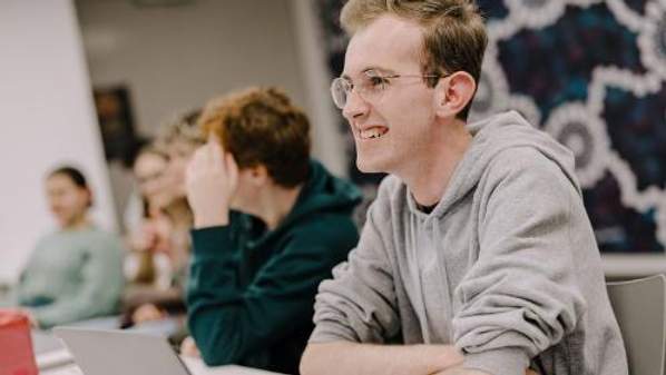 UOW Debating Society President, UOW student Sam Nicholls, smiles at a table during an internal debating club meeting. Photo: Michael Gray