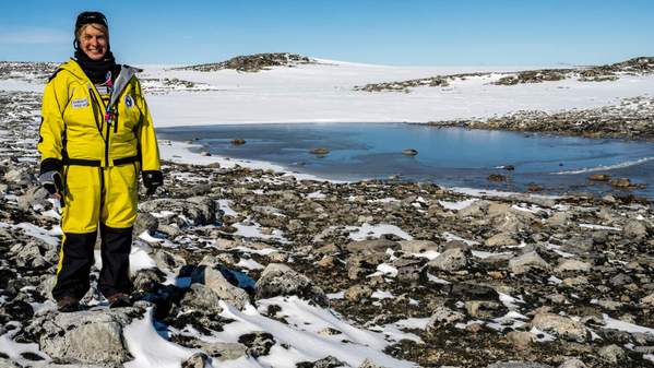 Sharon Robinson wears a yellow snow suit as she stands in the snow of Antarctica. Photo: Supplied