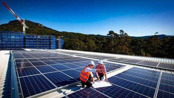 Engineers install solar panels on a building roof on the ý campus.