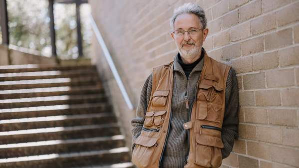 Dr Gert van den Bergh leans against a brick wall with a smile. Photo: Michael Gray