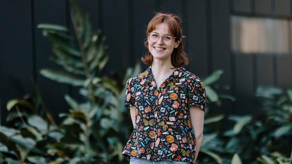 Alice O'Keefe has a big smile and stands in front of the Molecular Horizons Building. She wears jeans, a black shirt, and glasses. Photo: Michael Gray