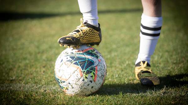 An image of a young man's foot perched on a football on a football field. Photo: Paul Jones