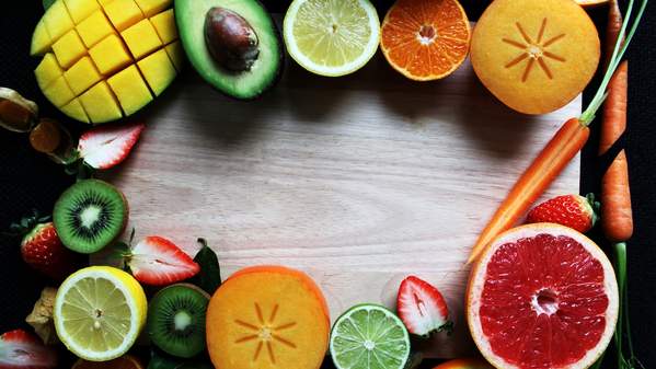 An array of fresh fruits and vegetables are spread out on a wooden board. Photo: Unsplash