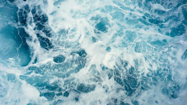 A close up image of frothy blue waves. Photo: Unsplash