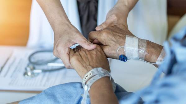 A doctor holds an elderly patient's hands