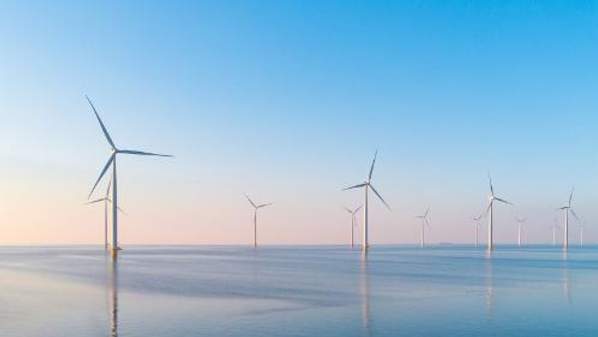 Wind power generating windmills in the ocean.