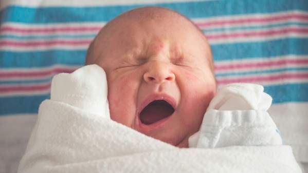 A newborn baby is wrapped in a hospital blanket. Photo: Unsplash