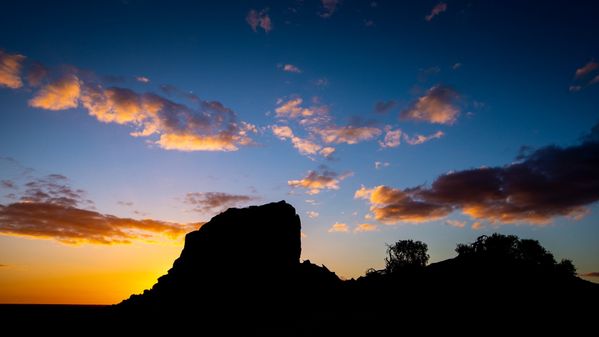 A landscape image of the sun setting over a large rock in Lake Mungo, in rural NSW. Photo: Paul Jones