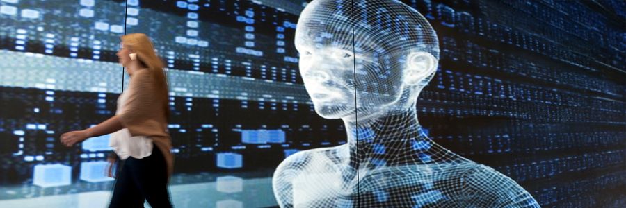 computer generated android on a screen looking toward 2 human women walking past