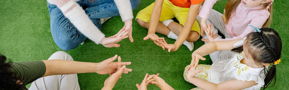 BIrdseye view of educators showing kids how to strectch their fingers