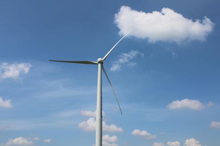 looking up at a wind turbine against a blue sky