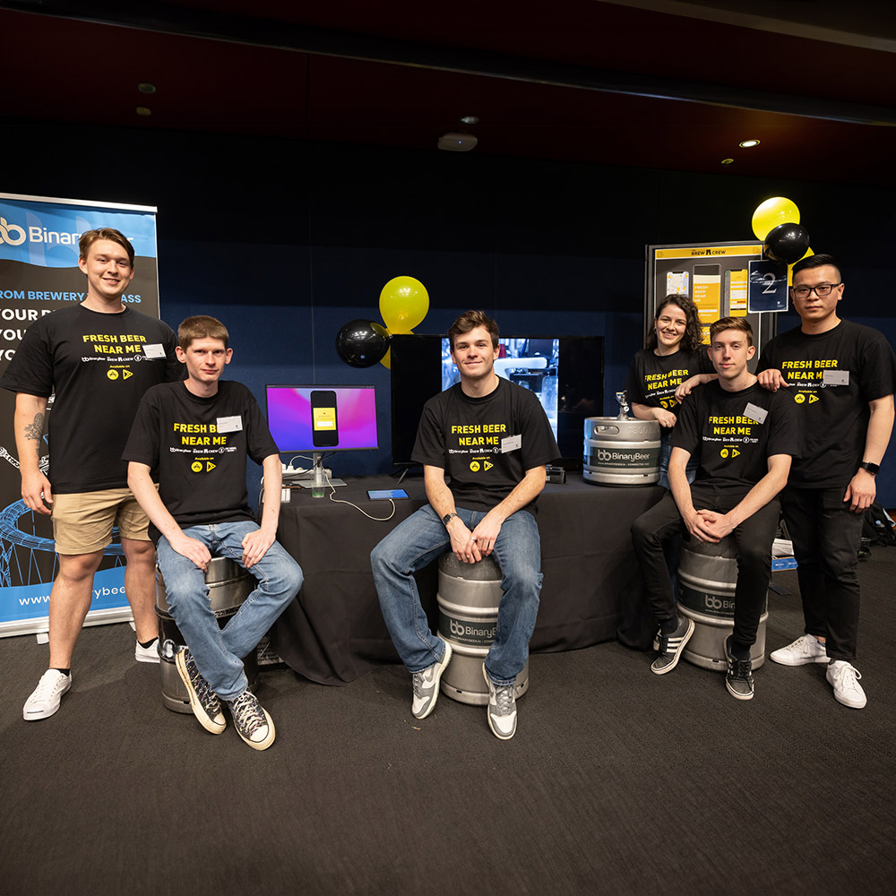 UOW students from the Faculty of Engineering and Information Sciences, stand among marketing material for their product, Binary Beer