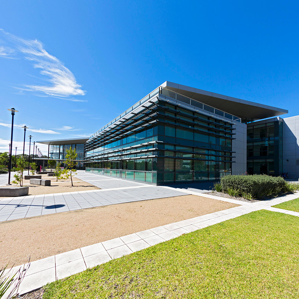 The Central  building at UOW's Innovation Campus set against a bright blue sky. A paved area is in the foreground.