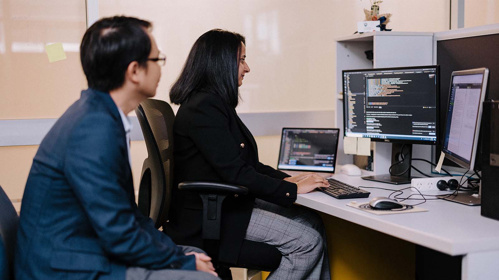 Man and woman looking at computer in modern office.