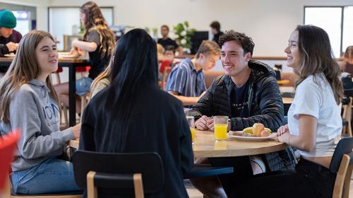 Students sitting at a table smiling and having breakfast