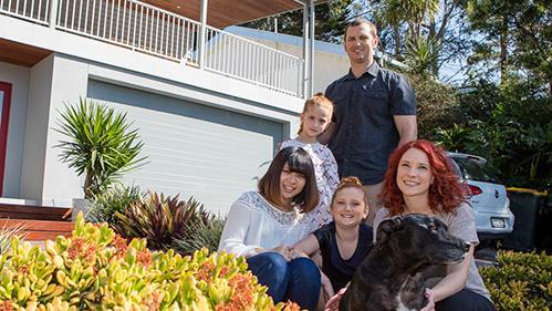 Family smiling together outside of their house