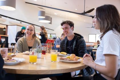 Students sitting around a table eating breakfast together