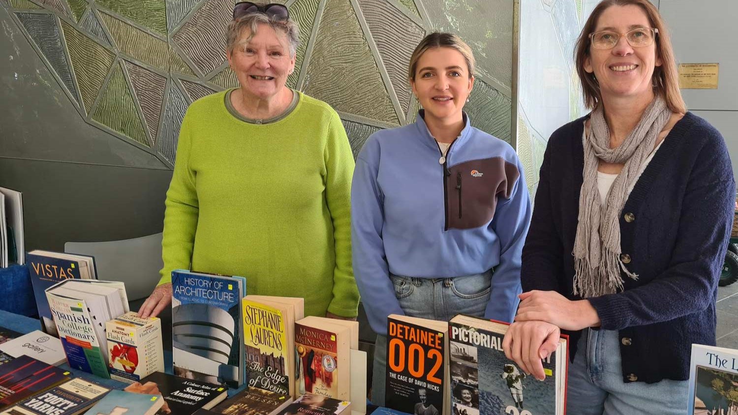 Alumni volunteers stand with their stall in front of the library on Markey Alley