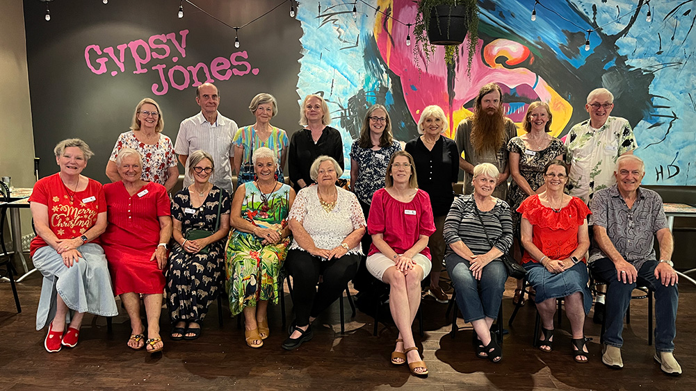Group photo of sixteen people smiling in a casual gathering at