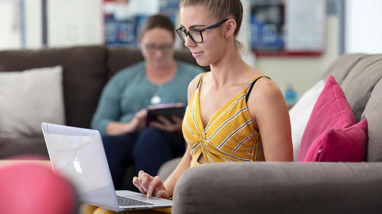A student uses a laptop on the couch at home