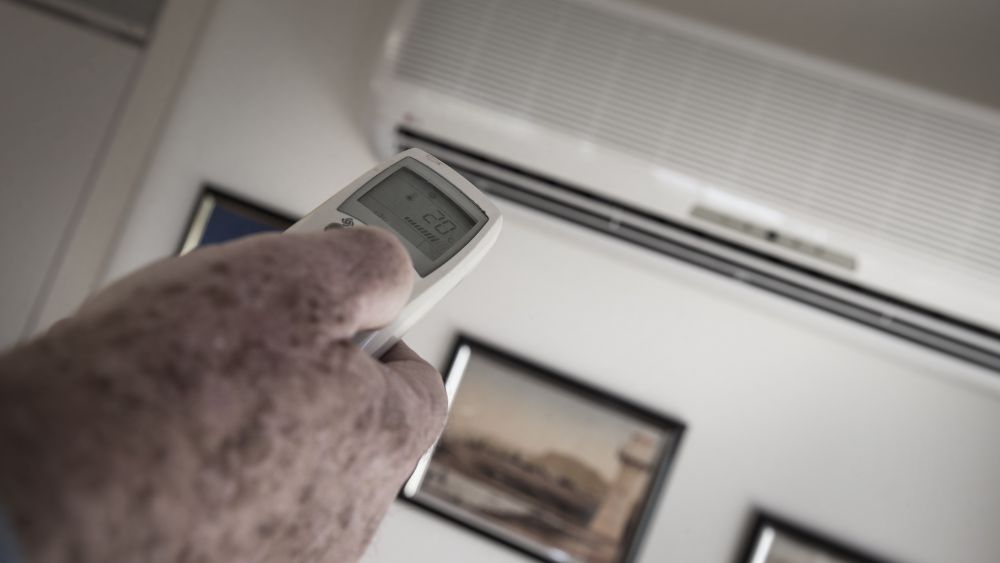 Air conditioner remote control being used by an elderly person