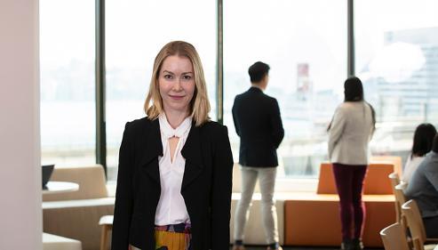 A female student stands in Sydney Business School with a view of the Harbour Bridge