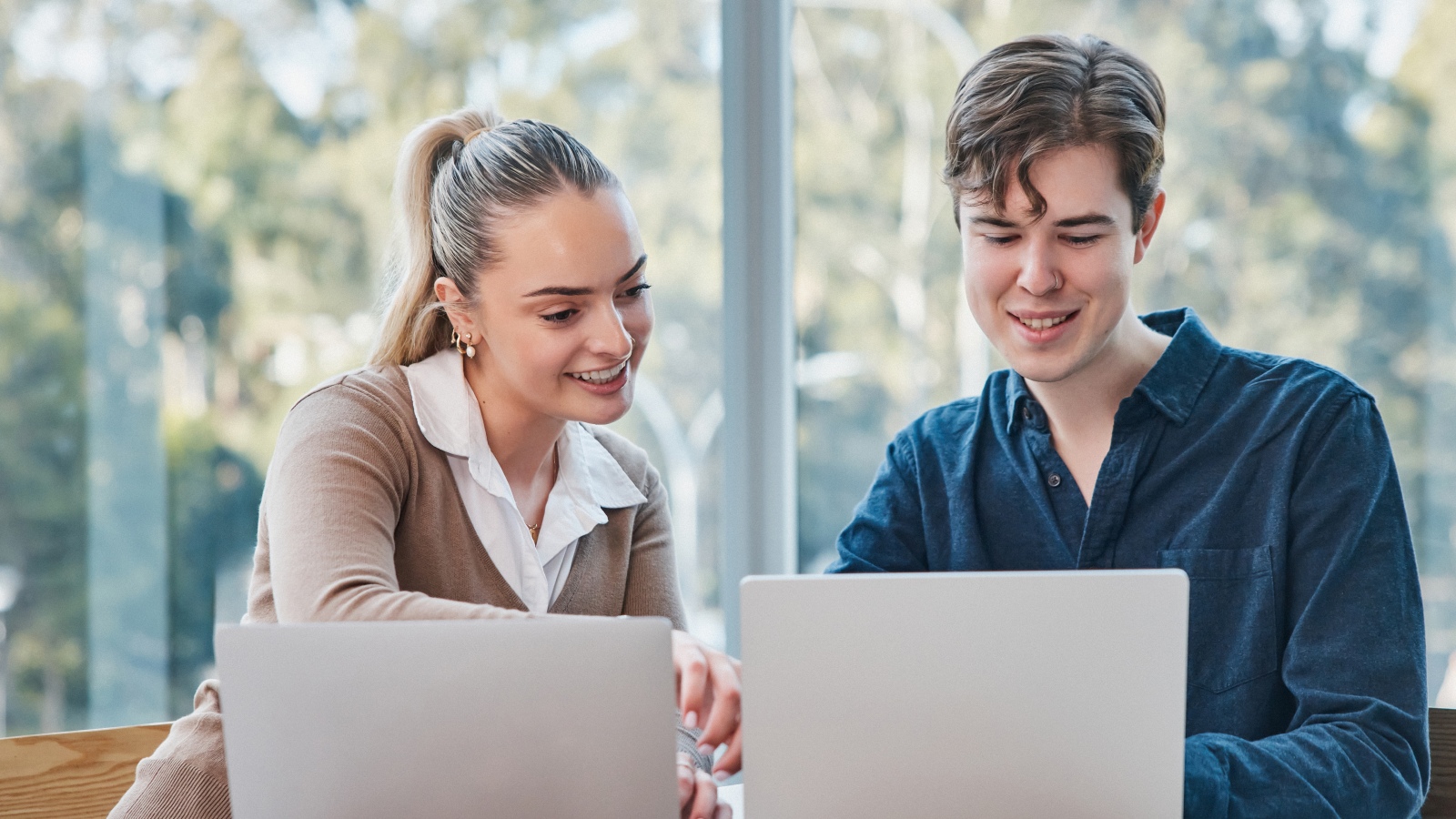 Two students explaining work next to each other with computers